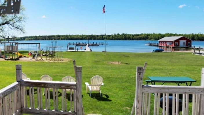 The lawn at Island View Resort running down to the water, with a playground, a flagpole, a dock and a red boathouse out on the bay.